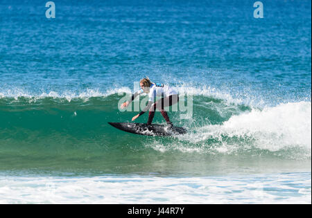 Jeune homme avec de longs cheveux blonds en compétition dans la compétition de surf barre oblique Werri, Gerringong, New South Wales, NSW, Australie Banque D'Images