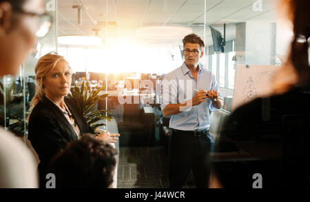 Man faire une présentation sur un tableau-papier et de discussions. L'équipe d'affaires au cours de réunion de stratégie, un bureau moderne. Banque D'Images