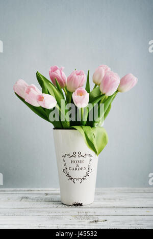 Bouquet de tulipes dans un vase rose sur fond bleu Banque D'Images