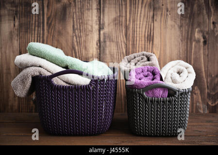 Les serviettes de bain de différentes couleurs dans des paniers en osier sur fond de bois Banque D'Images