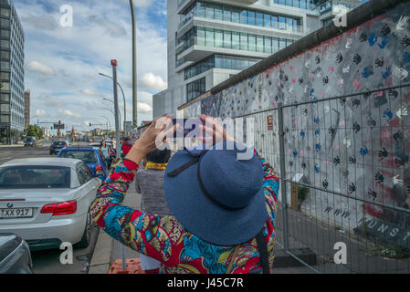 Les touristes de prendre des photos d'une section de la East Side Gallery sur Mühlenstrasse, Berlin, site des quelques dernières parties du mur de Berlin orné Banque D'Images