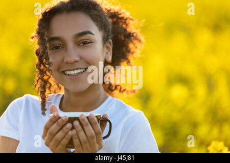 Beautiful happy mixed race African American girl teenager woman femme de boire du café ou du thé en plein air Banque D'Images