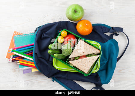 Boîte à lunch avec des légumes et un sandwich sur table en bois. Les enfants à emporter fort et sac à dos pour l'école. Vue d'en haut Banque D'Images