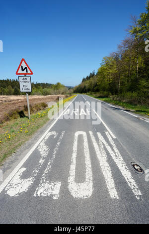 Affiche bilingue et marquages routiers dans le Nord du Pays de Galles dans les deux et gallois Enlish - un Saesneg Cymraeg. Panneau d'avertissement pour les virages de la route. Banque D'Images