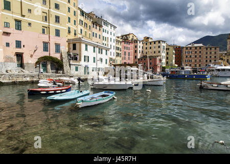 Scène portuaire paisible dans la station village de pêcheurs de Camogli, Italie sur la Riviera Italienne avec bateaux amarrés en face de maisons au bord de Banque D'Images