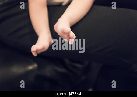 Close up of new born baby pieds sur un canapé en cuir noir dans des tons de couleur vintage avec chambre pour copy space Banque D'Images