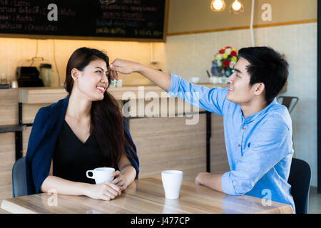 Belle femme asiatique sourire quand ses cheveux touchés par son petit ami dans le café. Banque D'Images