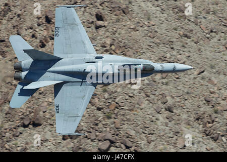 United States Navy F/A-18C, Hornet, volant à haute vitesse et faible niveau, à travers un canyon désert. Banque D'Images