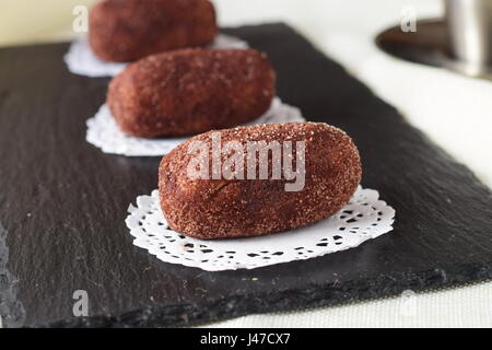 Des gâteaux de cuisson de pommes de terre sans nom sur un carrelage noir. Focus sélectif. Banque D'Images