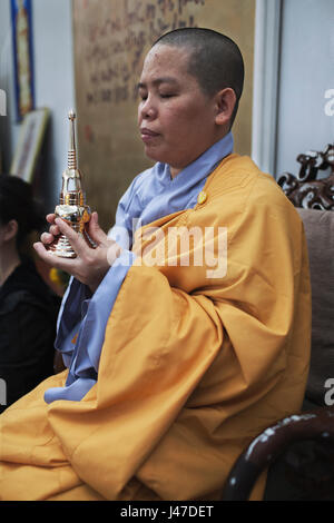 La nonne bouddhiste avec la tête rasée portant une robe jaune prier à l'intérieur d'un temple Banque D'Images