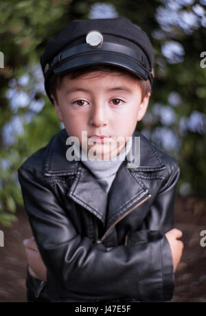 Le punk rock and roll petit garçon avec graisseur rockabilly coupe portant un blouson de moto en cuir noir et bleu denim jeans Banque D'Images