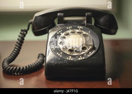 Vintage Retro Antique téléphone à cadran noir avec cordon enroulé sur un bureau en bois Banque D'Images