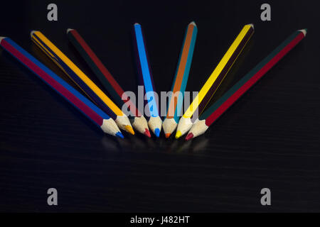 Crayons de couleur sur un fond de bois foncé, disposés en forme de ventilateur Banque D'Images