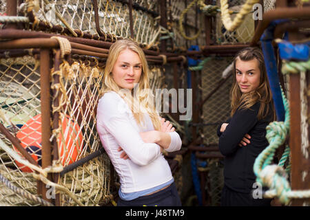 Portrait de deux jeunes femmes en face de la pêche commerciale du crabe Pots stockés dans le Port de King Cove, péninsule de l'Alaska Banque D'Images