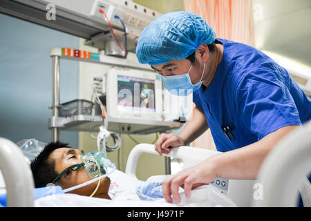 Zhengzhou, Chine, province de Henan. 9 mai, 2017. Liu infirmière Xiangda (R) vérifie un patient dans l'unité des soins intensifs (USI) de l'Hôpital Central de Zhengzhou à Zhengzhou, capitale de la province du Henan en Chine centrale, le 9 mai 2017. Liu, 25 ans, est l'un des plus de 70 hommes en soins infirmiers travaillant dans l'hôpital. Le nombre d'infirmières autorisées en Chine ont atteint 3,5 millions de dollars à la fin de 2016, selon les dernières statistiques de l'avant de la Journée internationale des infirmières, qui tombe le 12 mai. Crédit : Li Bo/Xinhua/Alamy Live News Banque D'Images