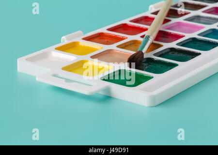 Aquarelle et pinceau en boîte blanche, sur fond bleu Banque D'Images
