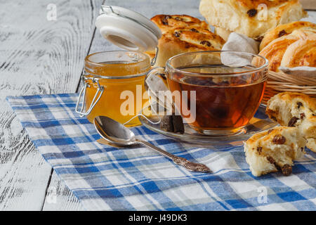 Concept de petit-déjeuner - sweet roll pain avec des raisins secs et une tasse de thé Banque D'Images