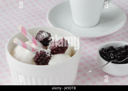 De délicieuses glaces avec de petits fruits surgelés et de la sauce, sur la couleur de fond de bois Banque D'Images