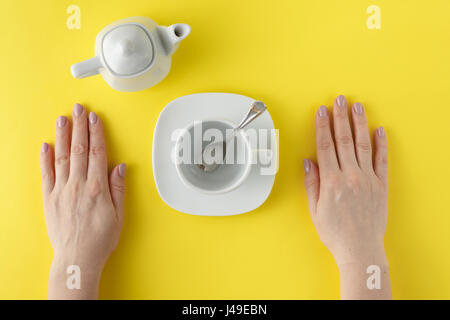 Théière et tasse blanche sur fond jaune Banque D'Images