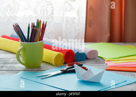 Ensemble de bateaux origami carré et feuilles de papier couleur sur une table en bois. Comment faire un origami simple navire. Tutoriel pliage de papier. Art pour enfants et de l'arc Banque D'Images