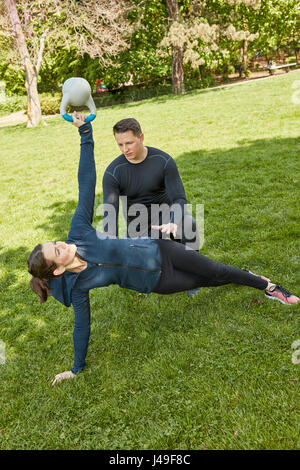 Femme avec kettleball en classe de formation de remise en forme personnelle au parc Banque D'Images