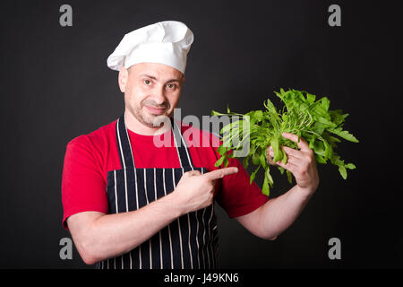 Gros plan du happy chef holding de roquette sur fond noir Banque D'Images