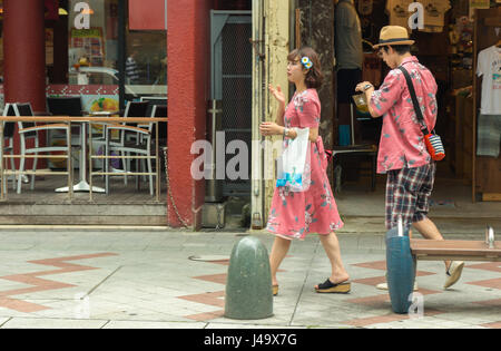 L'Okinawa, Japon - mars 24th, 2017 : un couple japonais portant des tenues correspondant marche sur le trottoir à Naha, Okinawa. Banque D'Images