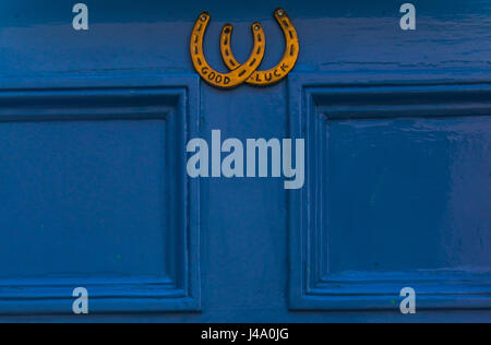 Porte en bois bleu en maison avec un heurtoir en laiton en forme de fer à cheval, avec les mots bonne chance, décoration chevaux Banque D'Images