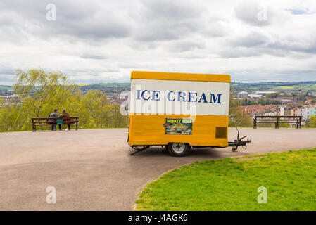 Petit jaune et blanc crème glace mobile shop avec couple sitting in banc admirant le paysage de la ville de Bristol. Brandon Hill Park, Bristol, Royaume-Uni. Banque D'Images