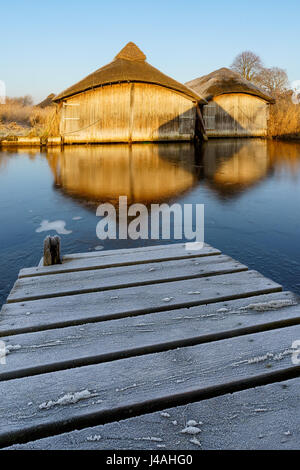 La première lumière captures ces beaux hangars à bateaux en bois sur un chaume hivers matin. Banque D'Images