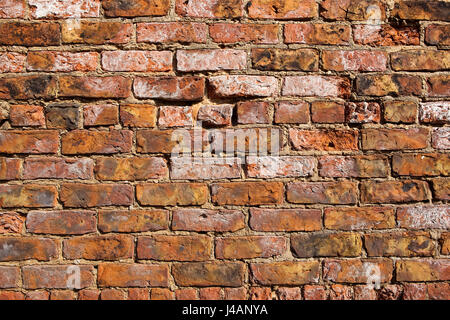 Un vieux mur de briques vieillies avec fond de ciment et d'anciennes briques colorées Banque D'Images