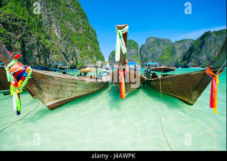 Bateaux longtail en bois traditionnel thaï avec des écharpes colorées dans les eaux turquoise de la baie de Maya d'Andaman, dans le sud de la Thaïlande Banque D'Images