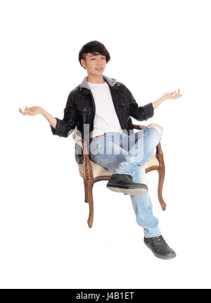 Un jeune homme asiatique assis dans un vieux fauteuil avec ses mains en l'air et dos de ne pas savoir quoi faire, isolée pour fond blanc. Banque D'Images