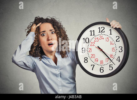 La pression du temps. Closeup portrait femme souligné du personnel de l'entreprise holding réveil anxieusement à court de temps gris isolé wall background. H Banque D'Images