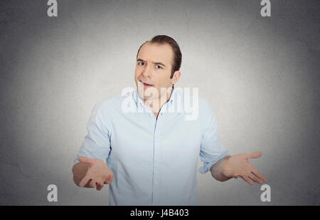 Closeup portrait of dumb clueless drôles de jeune homme, les bras de demander quel est le problème qui s'en soucie alors quoi, je ne sais pas, mur gris isolés retour Banque D'Images