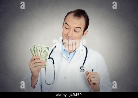 Closeup portrait avide avare grincheux professionnel de la santé, male doctor holding, protéger son argent dollars dans la main de mur gris isolé backgrou Banque D'Images