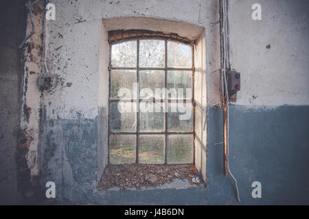 Fenêtre sur un vieux mur grunge avec des fissures et la peinture bleu pèle avec un interrupteur électrique à côté Banque D'Images