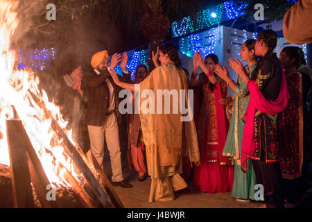 Le punjabi, hommes et femmes de la danse autour d'un feu à l'Lohri célébration dans la province du Punjab, en Inde. Banque D'Images