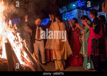 Le punjabi, hommes et femmes de la danse autour d'un feu à l'Lohri célébration dans la province du Punjab, en Inde. Banque D'Images