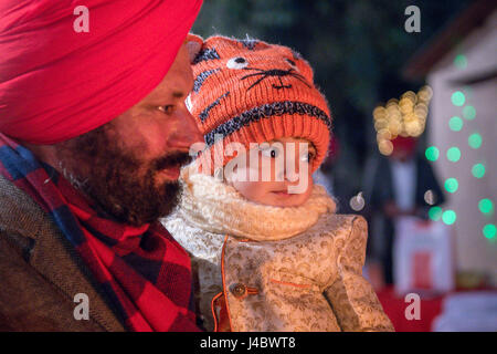 Un jeune enfant regarde dans la lumière du feu de camp à l'Lohri célébration dans la province du Punjab, en Inde. Banque D'Images