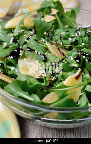 Salade de roquette (fusée) habillé avec sauce de soja balsamique , copeaux de parmesan et de poivre noir fraîchement moulu, de sésame. Tourné à la verticale. Banque D'Images