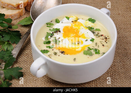 Crème de pommes de terre soupe avec du bacon et des œufs pochés, herbes, épices Banque D'Images