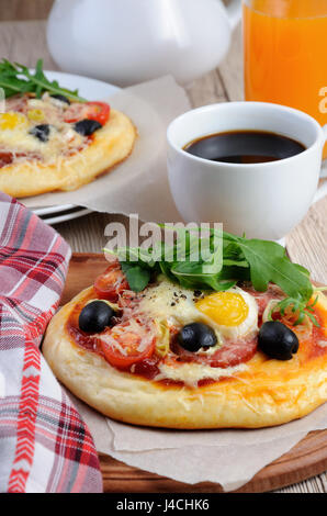 Mini pizza avec de la saucisse et l'oeuf et la roquette, une tasse de café Banque D'Images