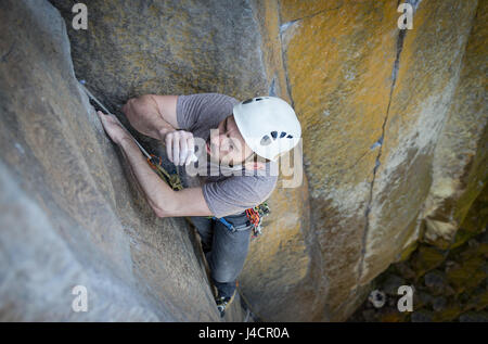 Young male climber chalk souffle au large de ses mains et qu'il repose sur une ascension vers le haut de Bandito, un crack trad dans la grotte, la Montagne de la table, de Jamestown, CA. Banque D'Images