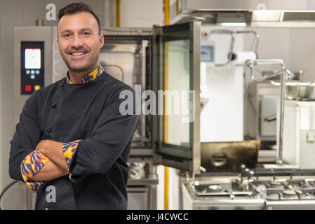 Young caucasian chef en cuisine smiling at camera Banque D'Images