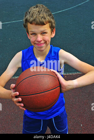 Jeune joueur de basket-ball tient le ballon avant le coup de feu Banque D'Images