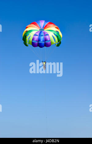 Parachutiste sur parachute coloré dans le ciel bleu ensoleillé. Mode de vie actif. Sport extrême. Banque D'Images