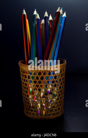 Conseils pointus de crayons de couleur à partir de sections d'affûtage d'un tube d'osier, sur un fond de bois foncé Banque D'Images