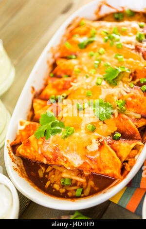 Enchiladas au poulet fait maison garnie d'oignons verts et la coriandre dans une casserole de blanc. Banque D'Images