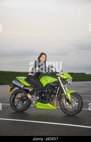 Fille brune sur une Triumph Street Triple moto dans une voiture aprk Banque D'Images